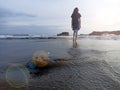 Blurry background of young woman standing alone on beach from behind watching sunset light over the sea. Inspirational backgrounds Royalty Free Stock Photo