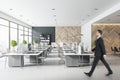 Blurry businessman silhouette in mosern light coworking office with light minimalistic furniture, wooden wall and big window