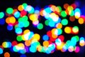 Blurry and colorful Christmas lights with yellow, red, green, light blue, navy blue, orange and white tones in a dark background. Royalty Free Stock Photo