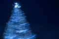 Blurry creative lighted christmas tree in monochrome classic blue palette on a dark background in trendy color of 2020. Xmas and Royalty Free Stock Photo