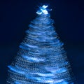 Blurry creative lighted christmas tree in monochrome classic blue palette on a dark background in trendy color of 2020. Xmas and Royalty Free Stock Photo