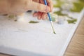 Blurry cropped photo of female hand painting with brush on paper, selective focus on acrylic paints Royalty Free Stock Photo