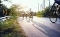 Blurry cyclist pedaling through sharp curve with long shadow on a sunny day.