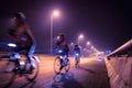 Blurry of Cyclists ride through lighted city.