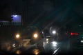 Blurry glare from headlights on windshield in bad rainy weather at night at traffic light