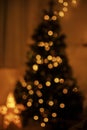 Blurry illuminated christmas tree in eve. Abstract blurred christmas tree with golden lights in evening room. Atmospheric Royalty Free Stock Photo