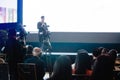 Blurry image of business people and cameraman with video camera set are recording to speaker and audience in conference hall or Royalty Free Stock Photo