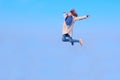 Blurry image of a happy teenage girl jumping up, blue sky background, horizontal view. People, freedom, travel concept. Royalty Free Stock Photo