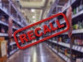 Blurry interior of a liquor store aisle behind large red Recall text Royalty Free Stock Photo