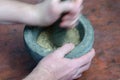 Blurry motion. A hand grinds with a pestle spices and herbs in a gray stone mortar Royalty Free Stock Photo