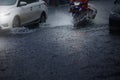 Blurry of motorcycle and cars run through flood water after hard rain fall.