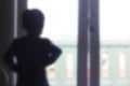 blurry photo of little boy standing looking out the window Royalty Free Stock Photo