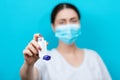 Blurry portrait of a female doctor in a medical mask showing an inhaler. Blue background. Copy space