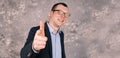 Blurry portrait of a young smiling modern businessman in glasses in a suit against the background of a gray concrete Royalty Free Stock Photo