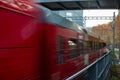 Blurry red passenger train carriage moving through urban Zurich Switzerland as seen from behind guard rails