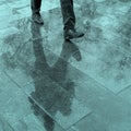 Blurry reflection legs and shadow, silhouette of a man in the wet sidewalk, in a puddle walking on a rain Royalty Free Stock Photo