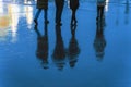 Blurry reflection legs and shadows, silhouettes of the men and women in the wet sidewalk, in a puddle, walk on a rain