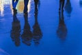 Blurry reflection legs and shadows, silhouettes of the people in the wet sidewalk, in a puddle of people hurrying on a Royalty Free Stock Photo