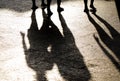 Blurry reflection shadow and silhouette of three people legs on summer bright sidewalk