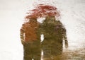 Blurry reflection silhouette in a puddle of couple holding hands