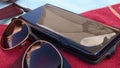 Blurry reflections in sunglasses and smartphone screen atop red towel at beach