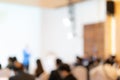 Blurry seminar hall with audience student in it. This room are arranged by round circle group table that appropriate for workshop