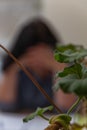 Blurry silhouette of a Brunette woman sitting at a table with her head in her hands. The concept of loneliness, despair