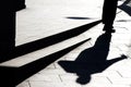 Blurry silhouette shadow of a man walking on a city sidewalk with steps in black and white Royalty Free Stock Photo