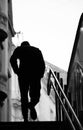 Blurry silhouette of a young man walking alone up the city subway stairs with hands in pockets