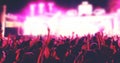 Blurry of silhouettes of concert crowd at Rear view of festival crowd raising their hands on bright stage lights Royalty Free Stock Photo
