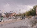 Blurry view through window with rain drops. Water drops on glass. Rainy cityscape from car Royalty Free Stock Photo