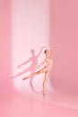 Blushing Balletic. Slim and tender woman, ballerina dancer in pink attire poses against subtle backdrop, her shadow