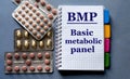 BMP - word in a notebook. Nearby are pills on a gray background