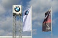 BMW banner flags and symbol outside the local dealer under a blue sky with clouds