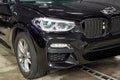 The BMW car, covered with a protective shiny black paint film, is in a repair shop, blurred focus. Chelyabinsk, Russia, May 07,