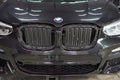 The BMW car, covered with a protective shiny black paint film, is in a repair shop, blurred focus. Chelyabinsk, Russia, May 07,