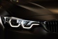 BMW car headlight illuminated against a black background. Royalty Free Stock Photo