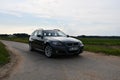 BMW 330d (E91) touring green-gray station wagon on country lane