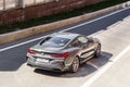BMW M850i coupe, rear side view. Aerial photography of a shiny gray car riding in Moscow streets on high speed