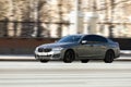 BMW 5 series G30 on the road in motion. Fast speed drive on city road. Front side view of moving gray car on the street