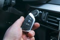 BMW X5 F15 start car key in a male hand near start/stop push button. Modern car interior details. The key to starting the engine