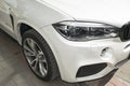 BMW X5 M Perfomance. Tire and alloy wheel. Headlight. Front view of a white modern luxury sport car. Royalty Free Stock Photo