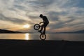 Bmx biker silhouette doing tricks against the sunset.