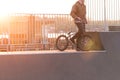 BMX cyclist is standing on a ramp skate park on the background of the sunset Royalty Free Stock Photo