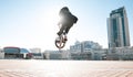 Bmx rider jumps on a bike on a sunny day, against the backdrop of urban scenery Royalty Free Stock Photo