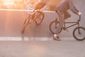 Bmx riders make tricks in a skate park on the background of the sunset. Evening training BMX cyclists. Bmx Concept