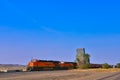 BNSF locomotives rolls past an old grain elevator along the tracks in Montana Royalty Free Stock Photo