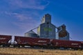 Bnsf rail cars race along the tracks in front of an old grain elevator in Montana