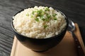 Board, bowl of delicious rice and spoon on wooden background Royalty Free Stock Photo
