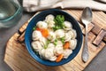 Board with bowl of dumplings in broth and spoon on table Royalty Free Stock Photo